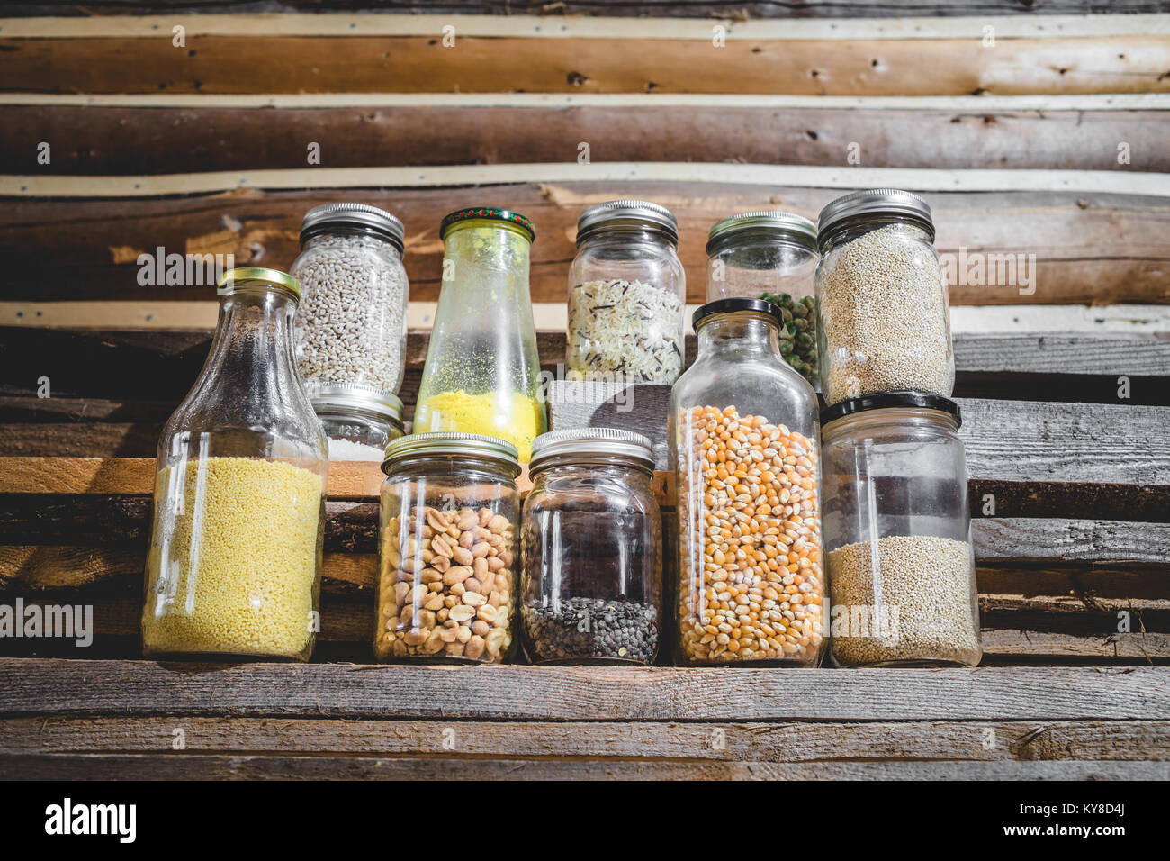 Peu de graines, de grains et de céréales dans des bocaux en verre avec fond de bois Banque D'Images