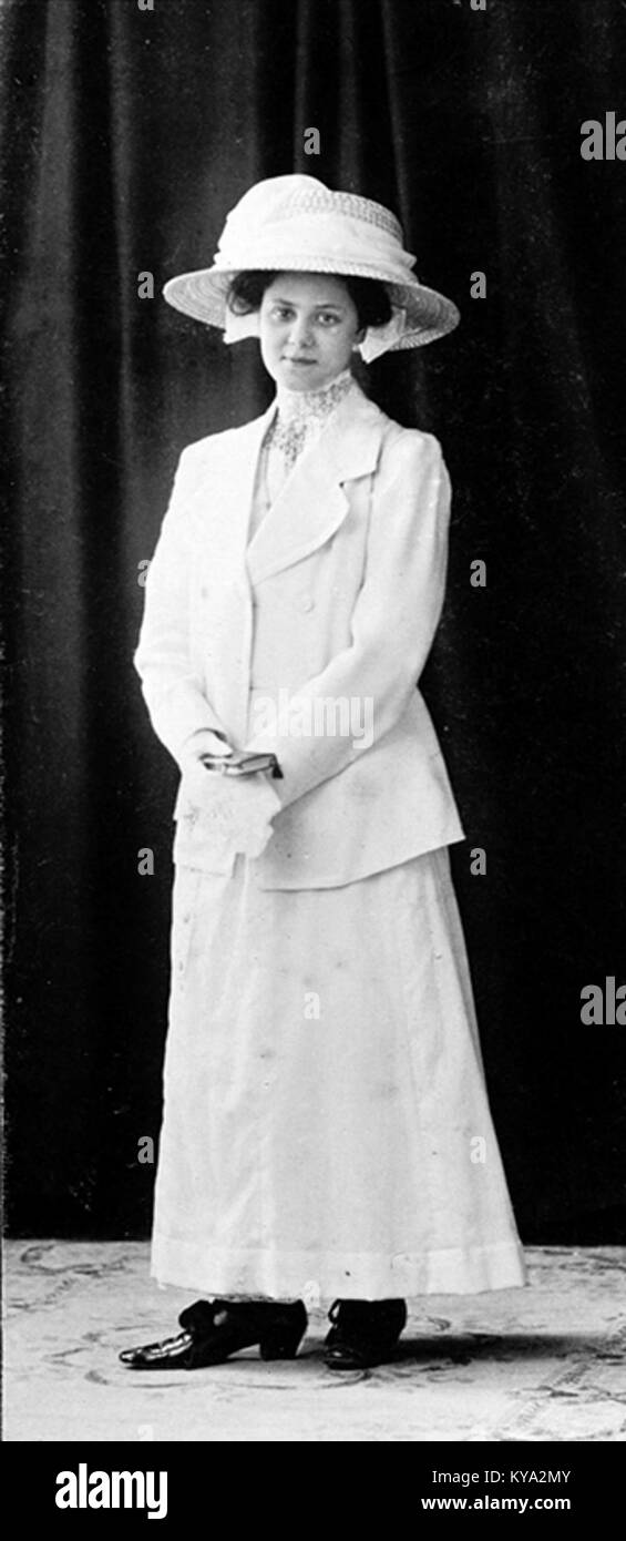 Cette image représente une femme vêtue d'une longue robe blanche et d'un chapeau, de la collection Nordiska Museet 'Vackra flickor förr i världen', illustrant la mode et le costume européens historiques. Banque D'Images