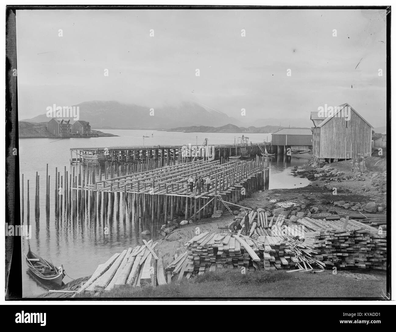 Cette photographie capture Wiigs Kai à Sandæssjøen, dans le comté de Nordland, en Norvège, montrant les structures côtières et les environs naturels de la région. L'image met en valeur l'environnement maritime norvégien et l'architecture côtière régionale. Banque D'Images