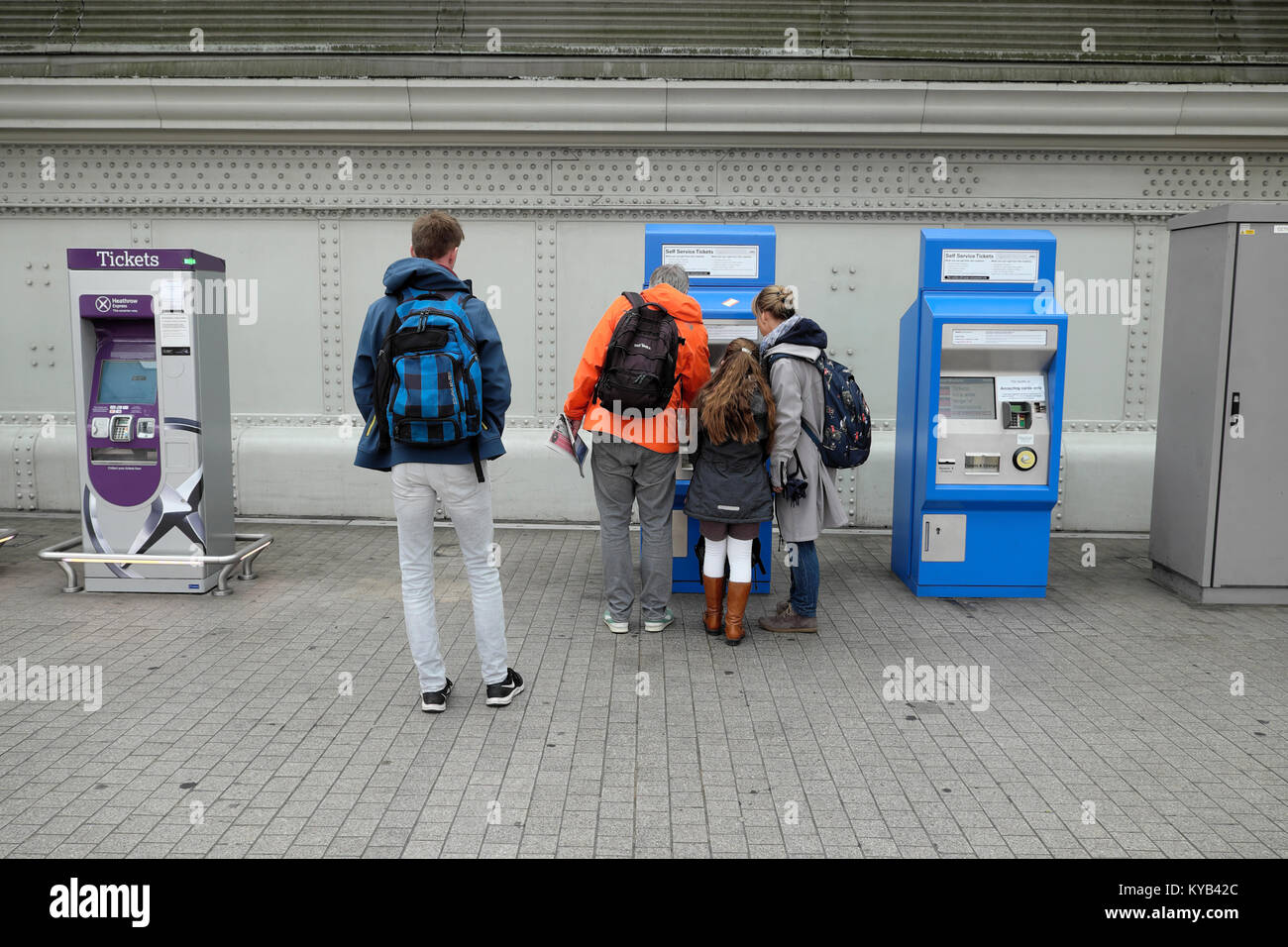 Un homme debout, attend une famille pour acheter des billets de train d'une nouvelle machine de billets à la gare de Paddington à Londres Angleterre Royaume-uni KATHY DEWITT Banque D'Images