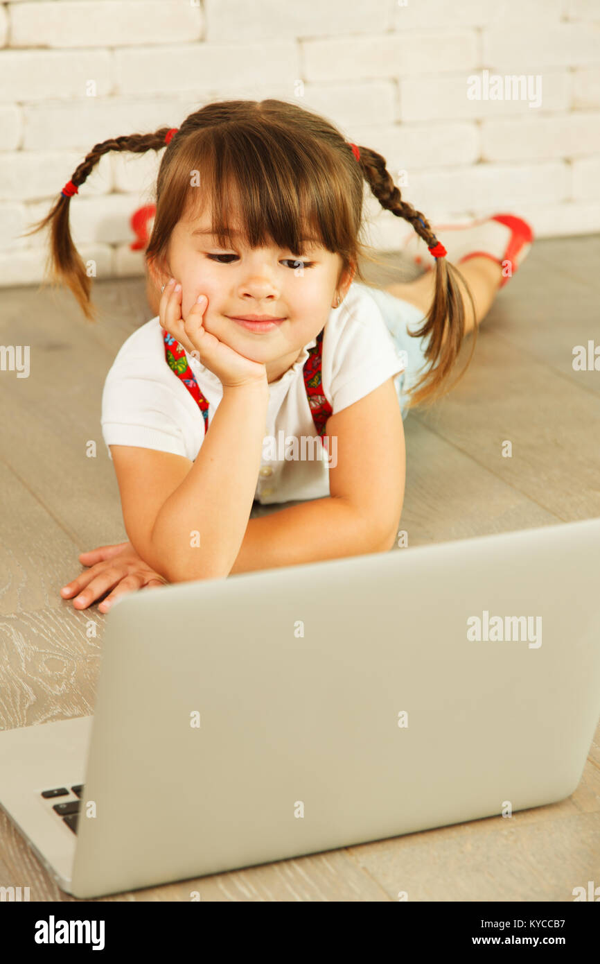 Bambin fille avec un ordinateur portable sur le plancher Banque D'Images