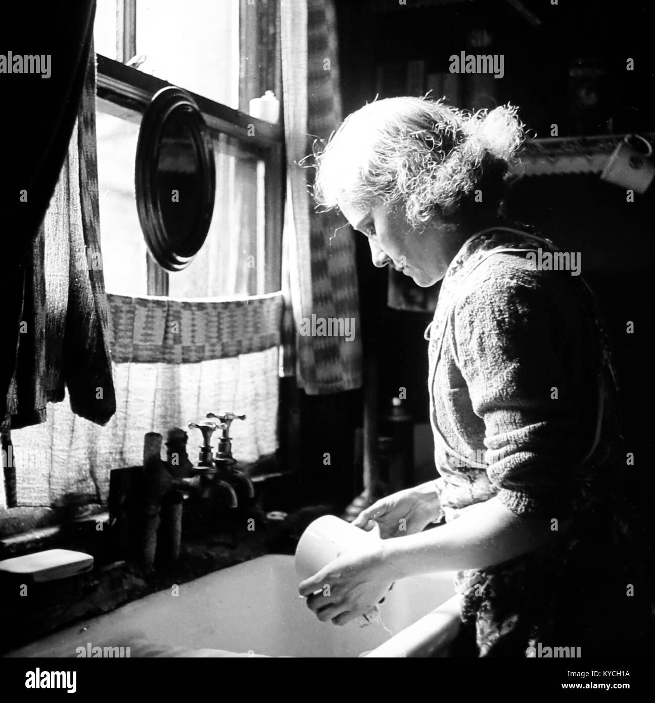 Femme au bord d'un évier de cuisine, probablement 1930 Banque D'Images