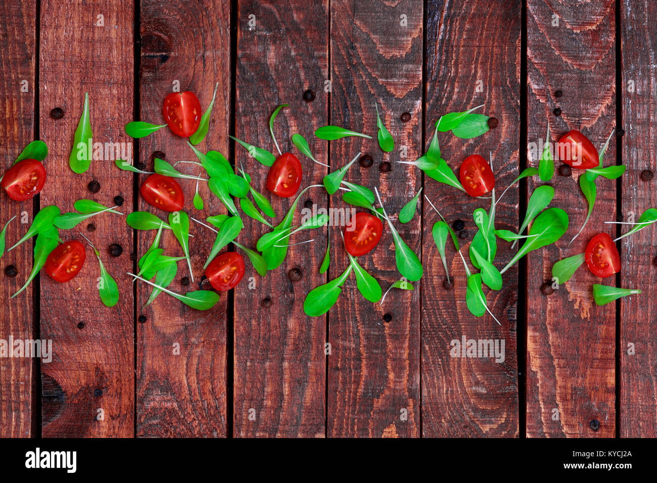 Fond de bois avec des feuilles de basilic et de tomates cerises. Copier l'espace, vue d'en haut. Banque D'Images