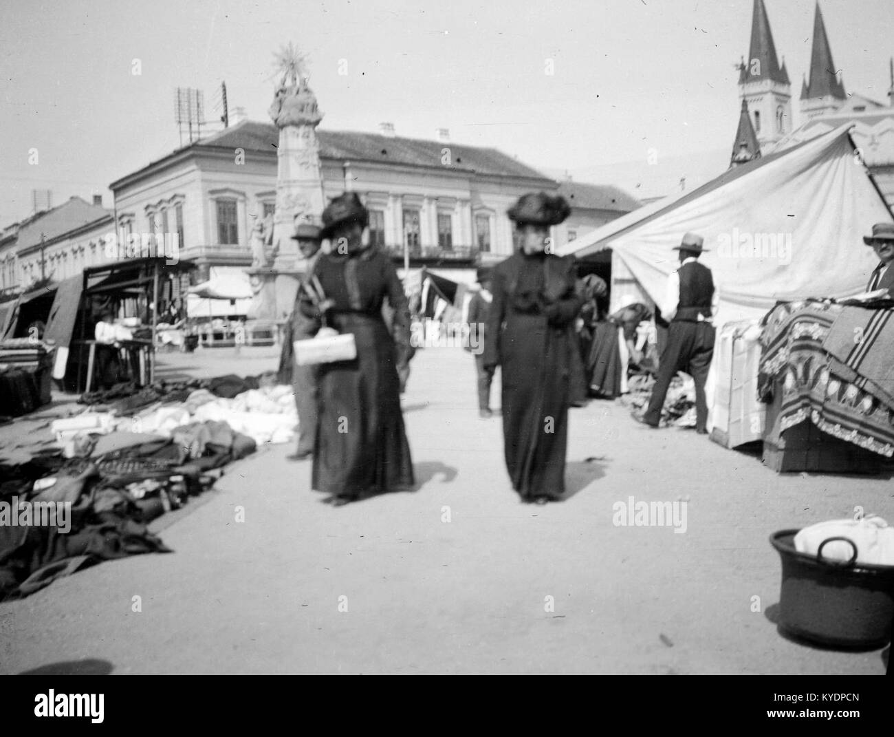 Photographie de la place Szent István à Budapest, Hongrie, montrant la statue de la Sainte Trinité (Szentháromság) au centre et les tours jumelles de l'église franciscaine (temploma Barátok) à droite, capturant les éléments historiques et architecturaux de la place. Banque D'Images