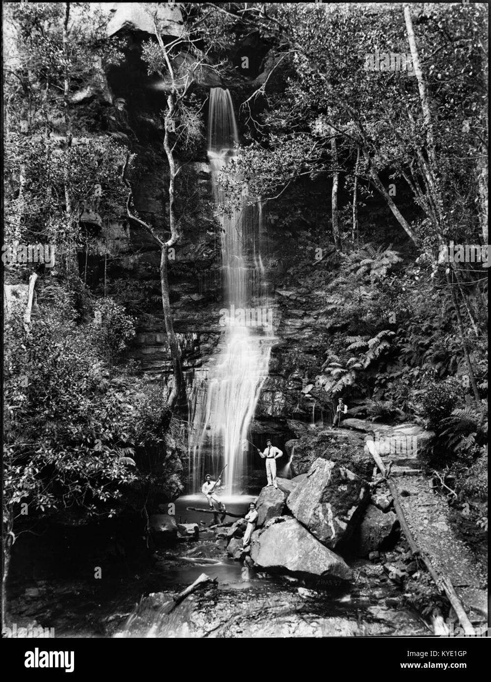Photographie montrant trois hommes pêchant à la base d'une cascade, représentant un paysage naturel et une activité récréative en plein air. Banque D'Images