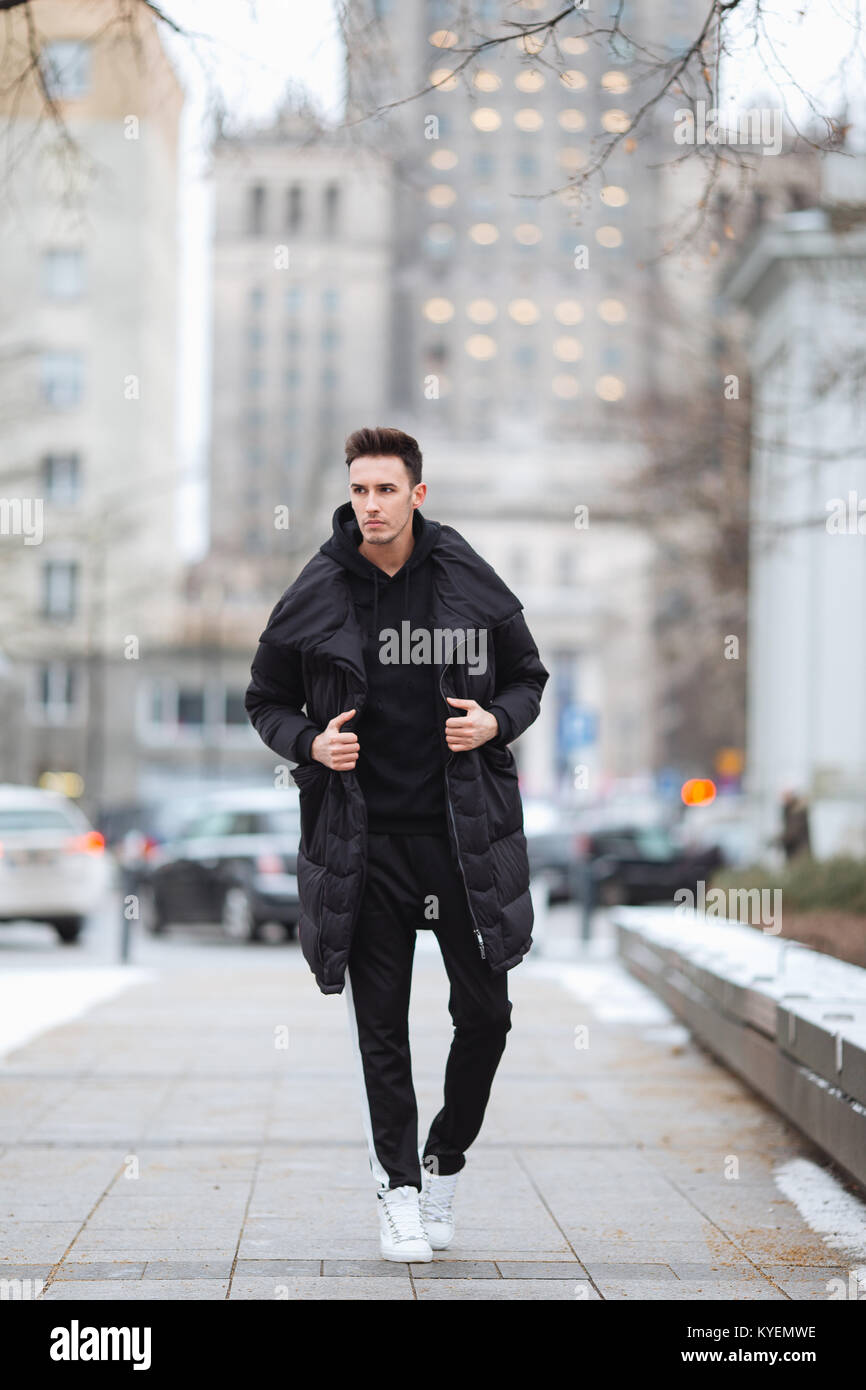 L'homme élégant wolk dans la rue. Froid d'hiver tenue. Veste avec Big White  sneakers. Fond Blured street. Modèle photo Profecional Photo Stock - Alamy