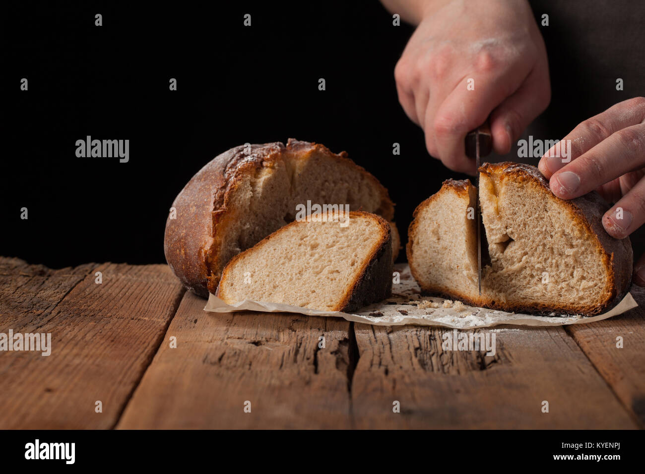 Man tranches de pain frais et délicieux sur fond noir avec l'exemplaire de l'espace pour votre texte. Le pain sur la table rustique ancienne Banque D'Images