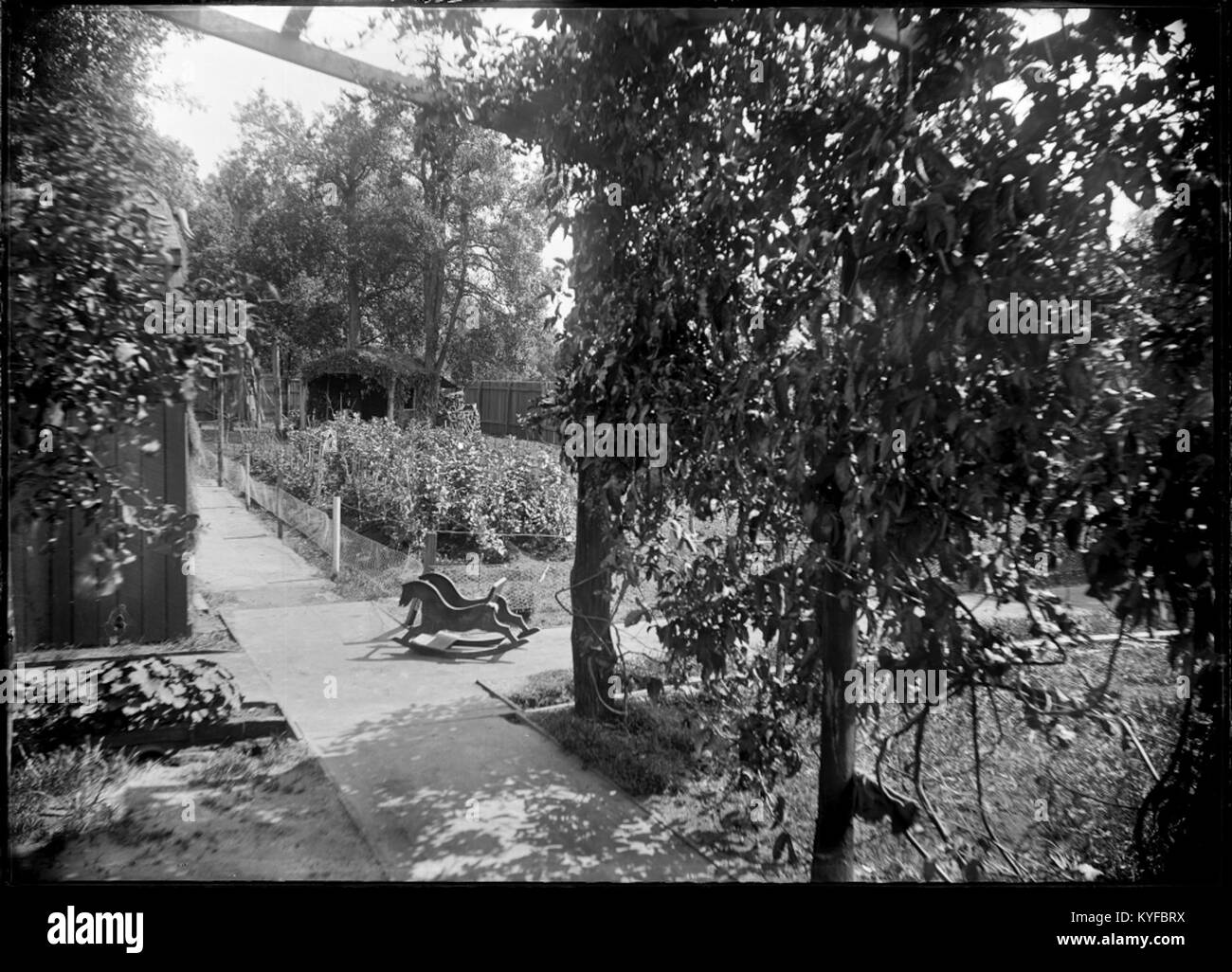Cette photographie représente un potager clos avec un cheval à bascule en bois au centre, montrant la disposition du jardin, la culture des plantes et les activités domestiques en plein air. Banque D'Images