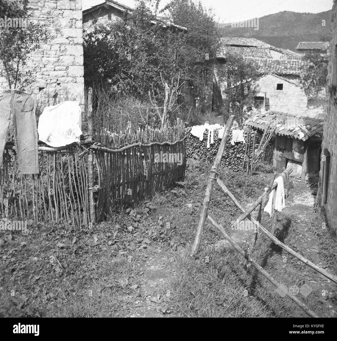 Photographie de 1951 à Robidisce, Slovénie, montrant un jardin rural, une clôture, une pile de bois et une petite maison pour la fabrication du fromage, reflétant la vie rurale du milieu du XXe siècle Banque D'Images