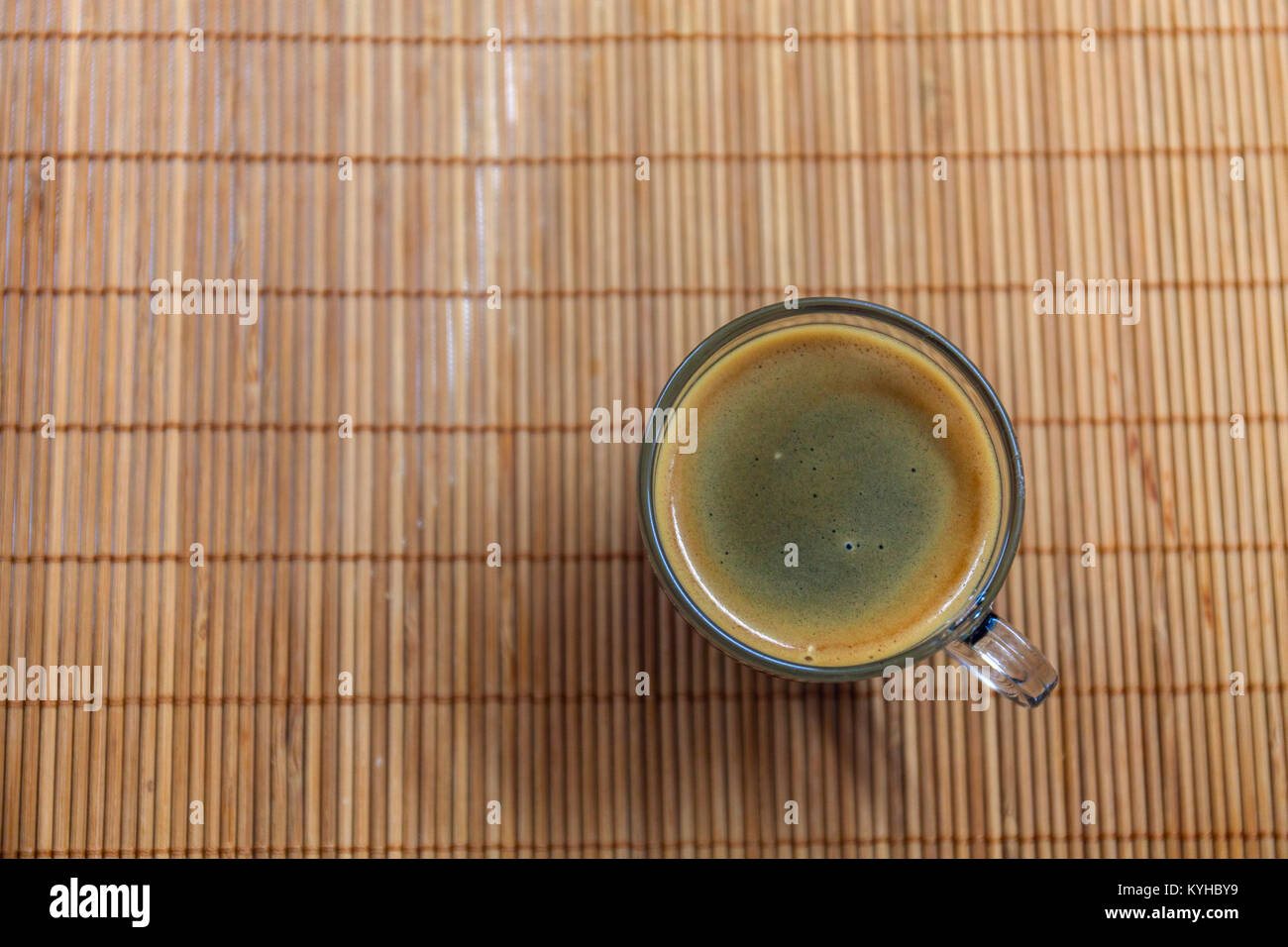 Machine à café expresso avec golden-fine crème bullées vu de dessus dans un crystal clear cup le porte-plaque en bambou. Banque D'Images