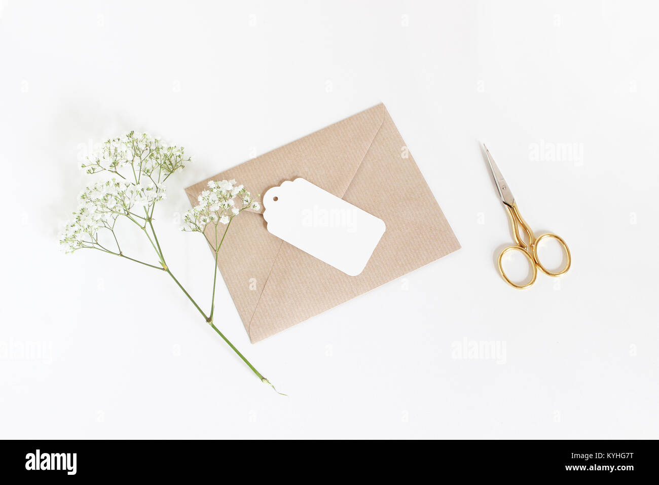 White gift tag avec enveloppe de papier craft, or et gypsophile Gypsophila fleurs isolé sur fond blanc. Mariage ou anniversaire disant stock photo, vue d'en haut, jeter la composition. Banque D'Images