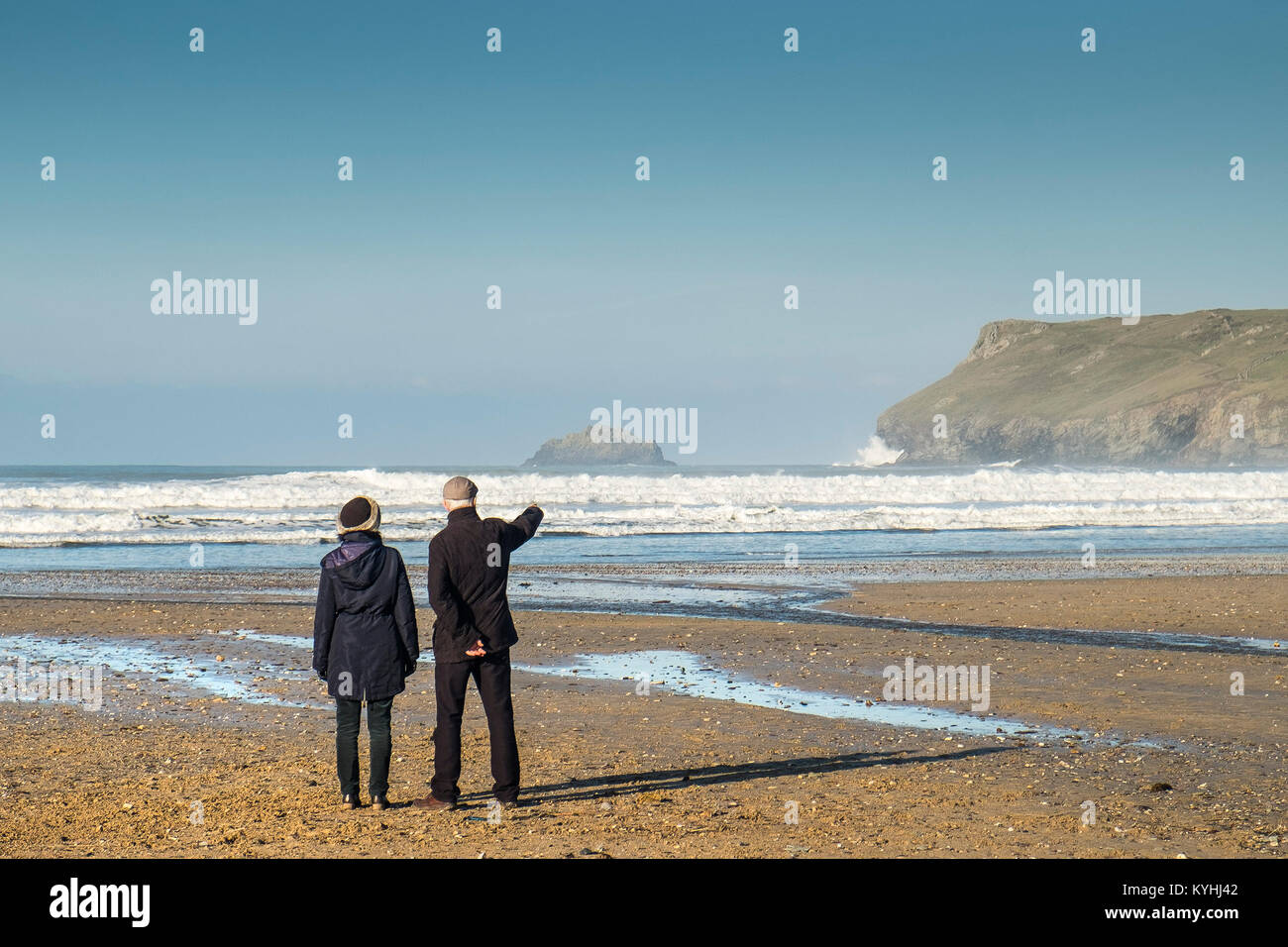 Polzeath - un couple de personnes debout sur la plage de Polzeath profitant de la vue sur la côte nord des Cornouailles. Banque D'Images Polzeath - un couple de personnes debout sur la plage de Polzeath profitant de la vue sur la côte nord des Cornouailles. Banque D'Images