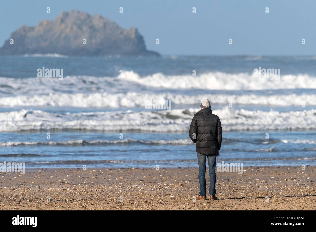 Polzeath - un homme debout sur la plage de Polzeath sur la côte nord des Cornouailles. Banque D'Images