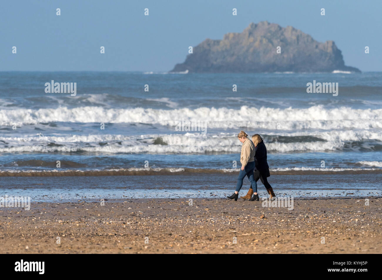 Polzeath - deux personnes Femmes marchant le long du rivage sur la plage de Polzeath sur la côte nord des Cornouailles. Banque D'Images