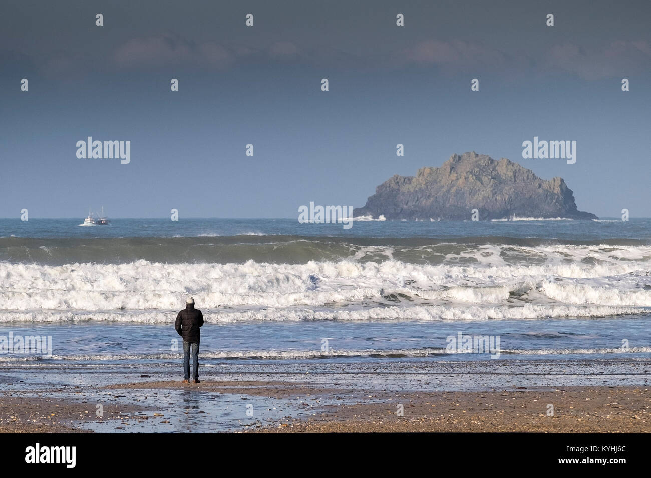 Polzeath - un homme debout sur le rivage sur la plage de Polzeath sur la côte nord des Cornouailles. Banque D'Images