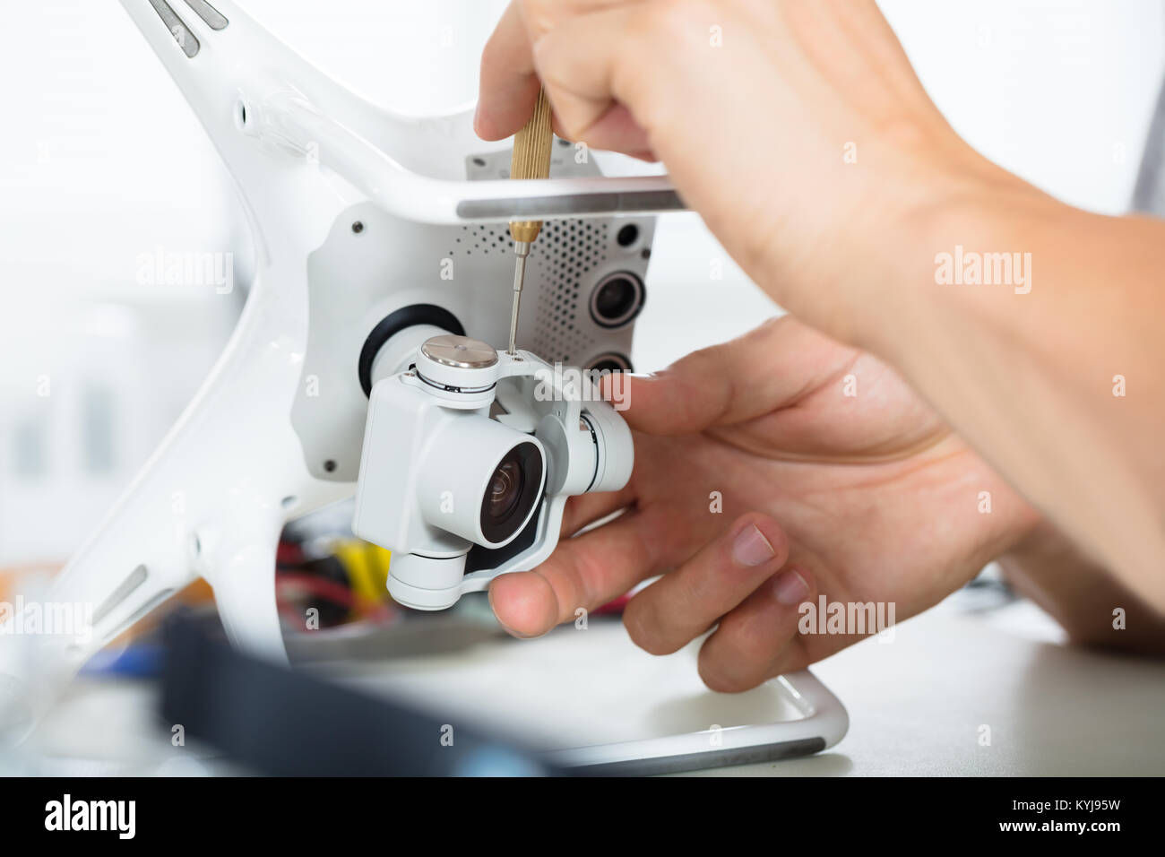 La main du mâle de la réparation de l'appareil photo d'action sur Quadrocopter Drone à table avec l'outil en atelier moderne Banque D'Images