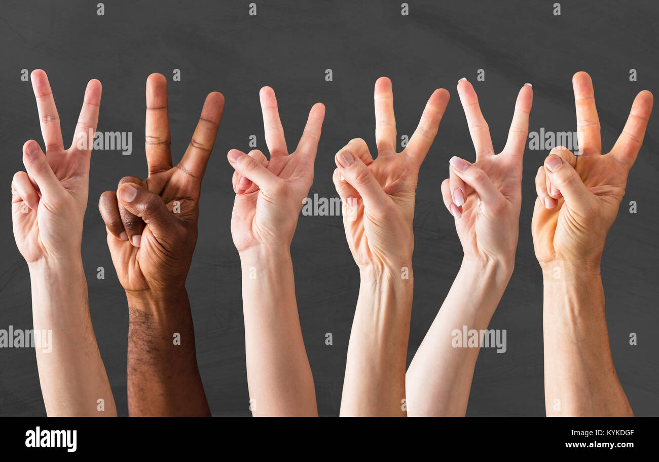 Groupe de mains montrant le signe de paix sur tableau noir Banque D'Images
