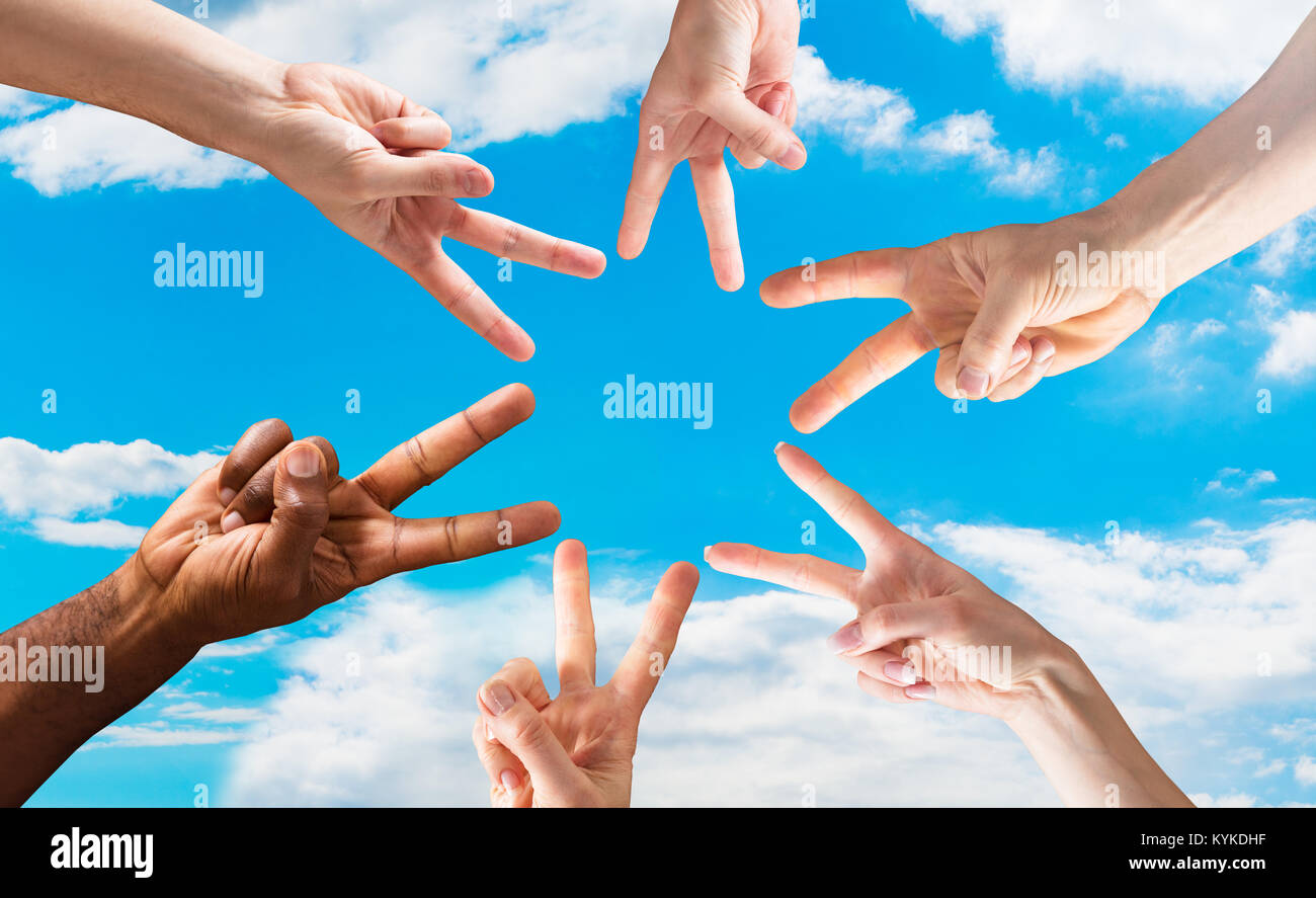Groupe de mains montrant le signe de paix contre le ciel bleu en cercle Banque D'Images