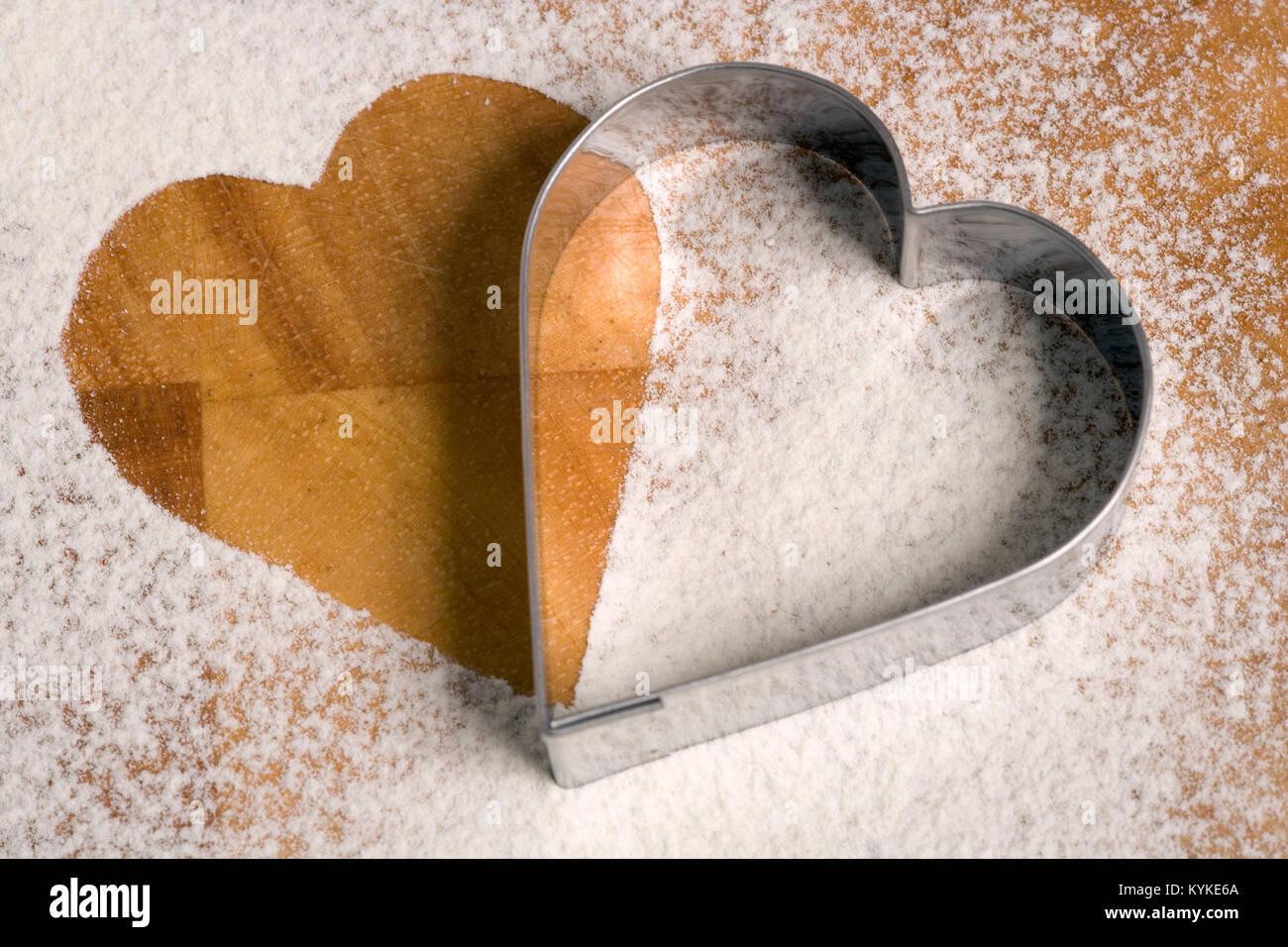 Emporte-pièce en forme de cœur sur un plan de travail saupoudré de farine Banque D'Images