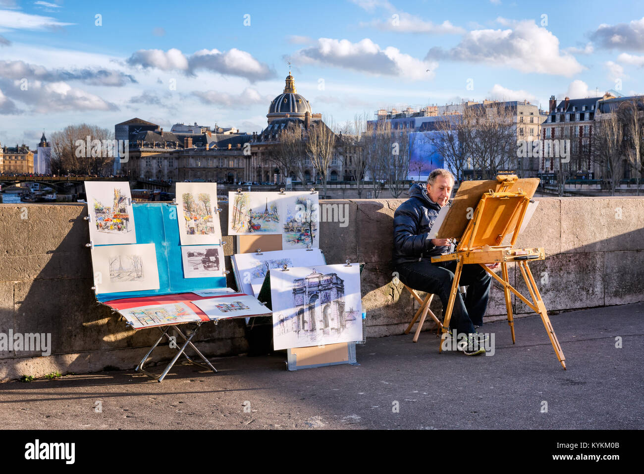 PARIS-JAN 2, 2014 : Un peintre non identifié au travail avec son chevalet et d'une exposition de ses oeuvres à vendre sur Pont Neuf, le plus vieux pont sur la Seine. H Banque D'Images