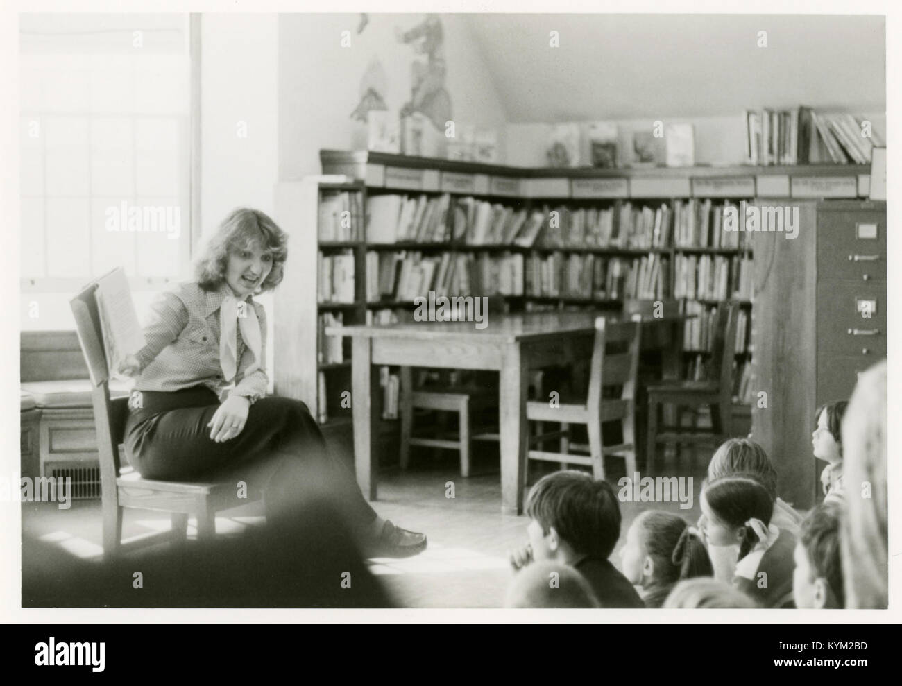 Illustration nostalgique représentant un bibliothécaire lisant un livre aux enfants pendant le temps du conte à la bibliothèque de Kenilworth, reflétant une ère révolue de la culture de bibliothèque. Banque D'Images