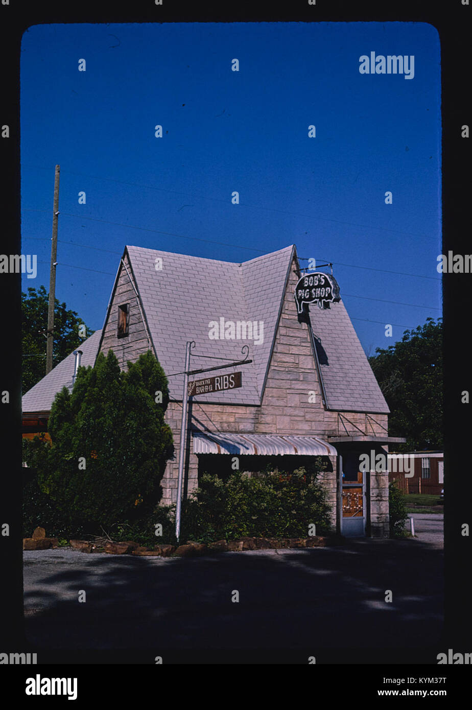 Une photographie verticale historique de la station-service Bob's Pig Shop et du restaurant barbecue sur la route 77 à Pauls Valley, Oklahoma, montrant les détails architecturaux de la station-service et son association avec la culture alimentaire locale. Banque D'Images