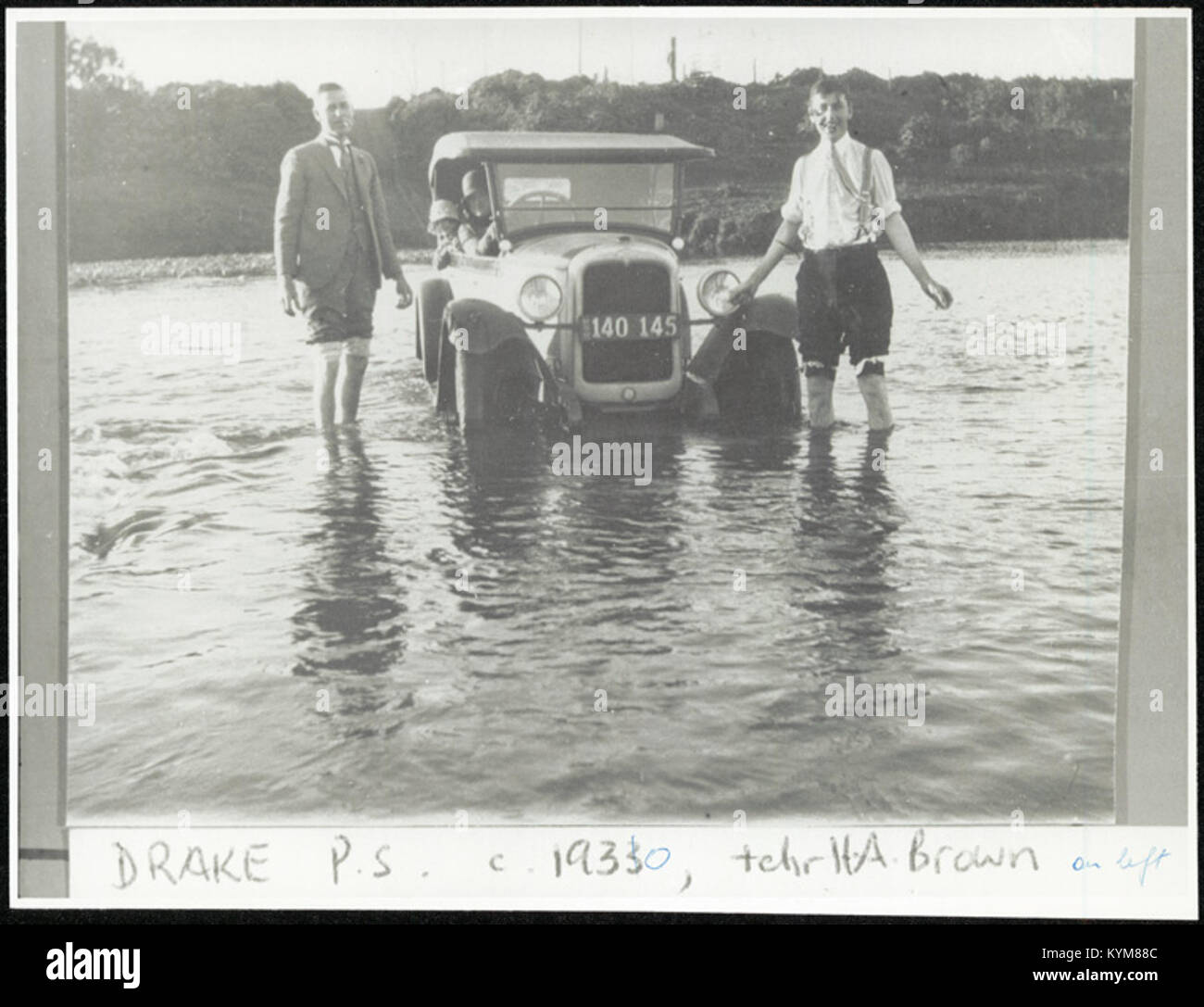 Photographie de l'enseignant H.A. Brown avec des élèves de l'école publique Drake, montrant une voiture traversant une rivière, illustrant les activités scolaires du début du XXe siècle. Banque D'Images