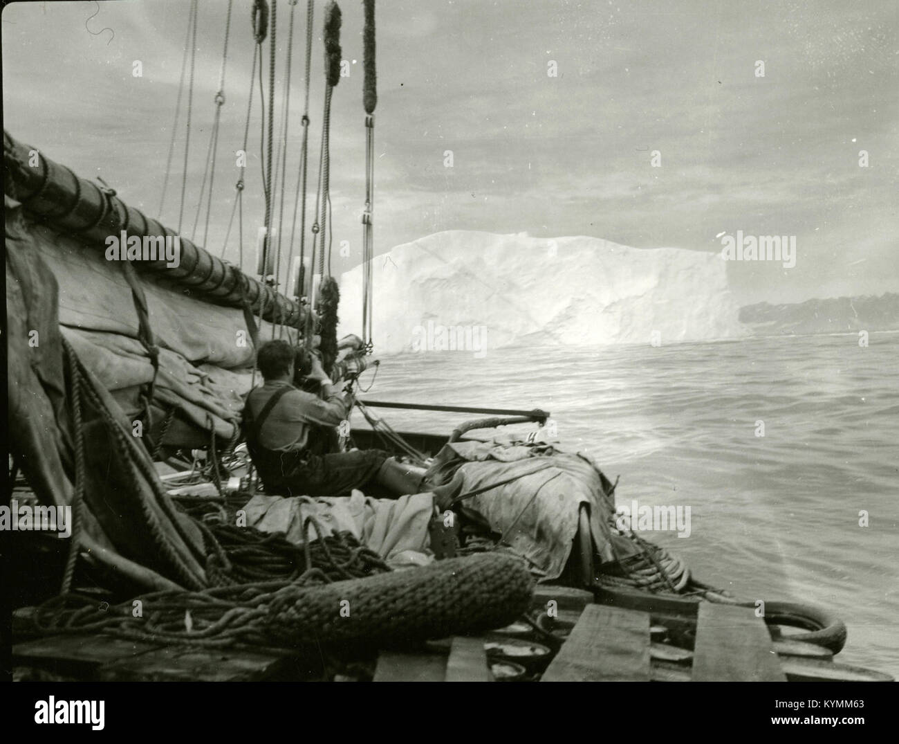 Photographie historique d'un membre d'équipage de l'escadron no 47, capturant un film d'un iceberg au cours d'une expédition, probablement du début du XXe siècle. Banque D'Images