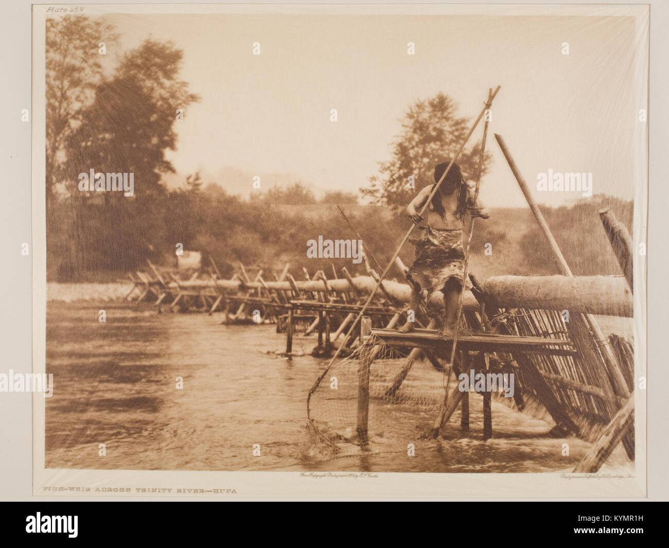 La photographie d'Edward Curtis capture un déversoir de poissons de l'autre côté de la rivière Trinity dans le territoire de Hupa. L'image fait partie d'une collection historique documentant la vie et la culture amérindiennes au début du XXe siècle. Banque D'Images