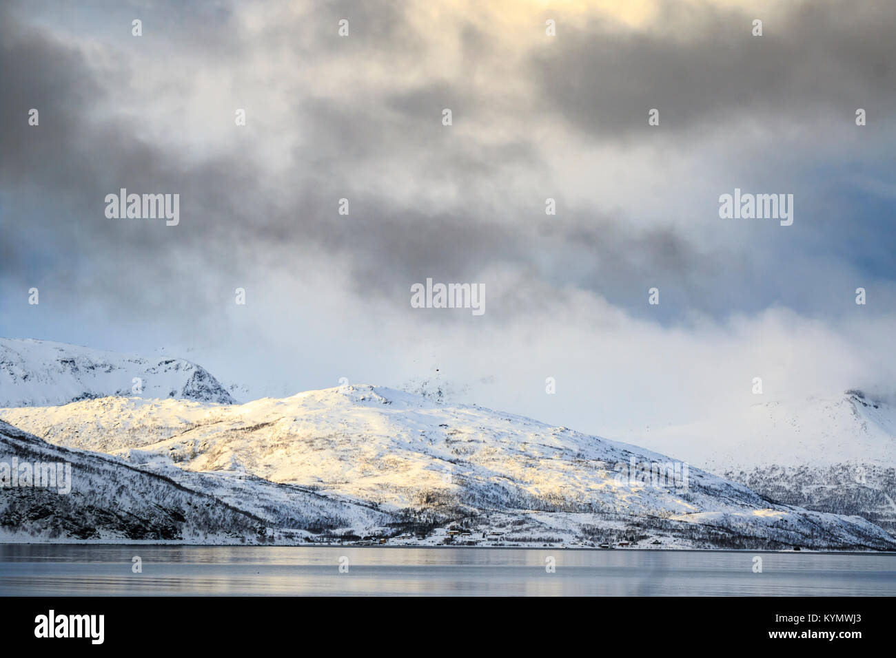 Côte norvégienne typique avec une tempête de neige en entrant un fjord comté de Troms, Norvège. Montagnes couvertes de neige pendant l'hiver froid. Banque D'Images