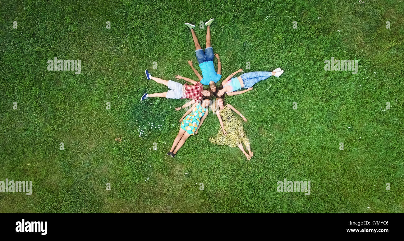 Groupe de jeunes adultes laying in grass dans la formation des étoiles Banque D'Images