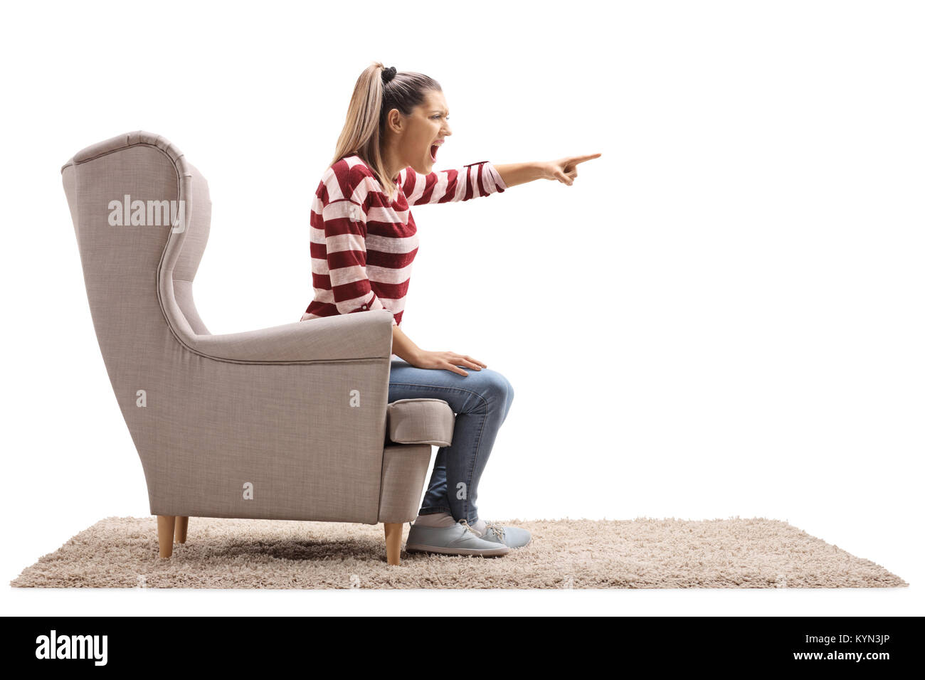 En colère jeune femme assise dans un fauteuil et se disputer avec quelqu'un d'isolé sur fond blanc Banque D'Images