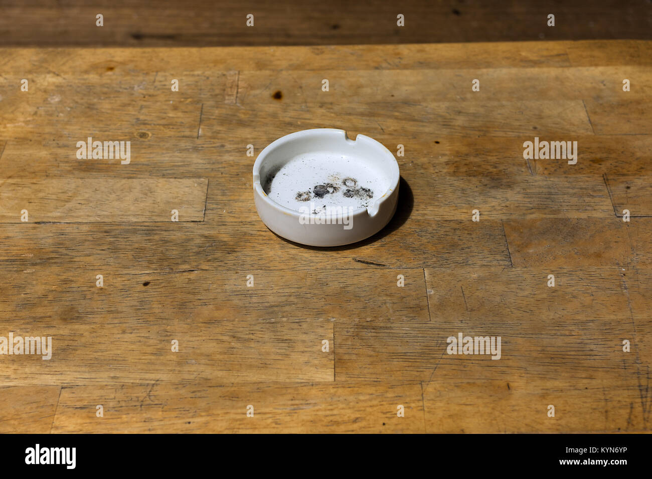 Utilisé en céramique blanc sale cendres de cigarette bac sur une table en bois prévu dessus. Banque D'Images