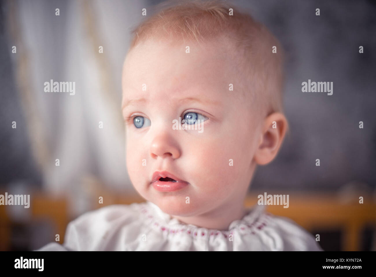 Un mignon petit bébé avec des cheveux blonds et des yeux bleus est à côté Banque D'Images