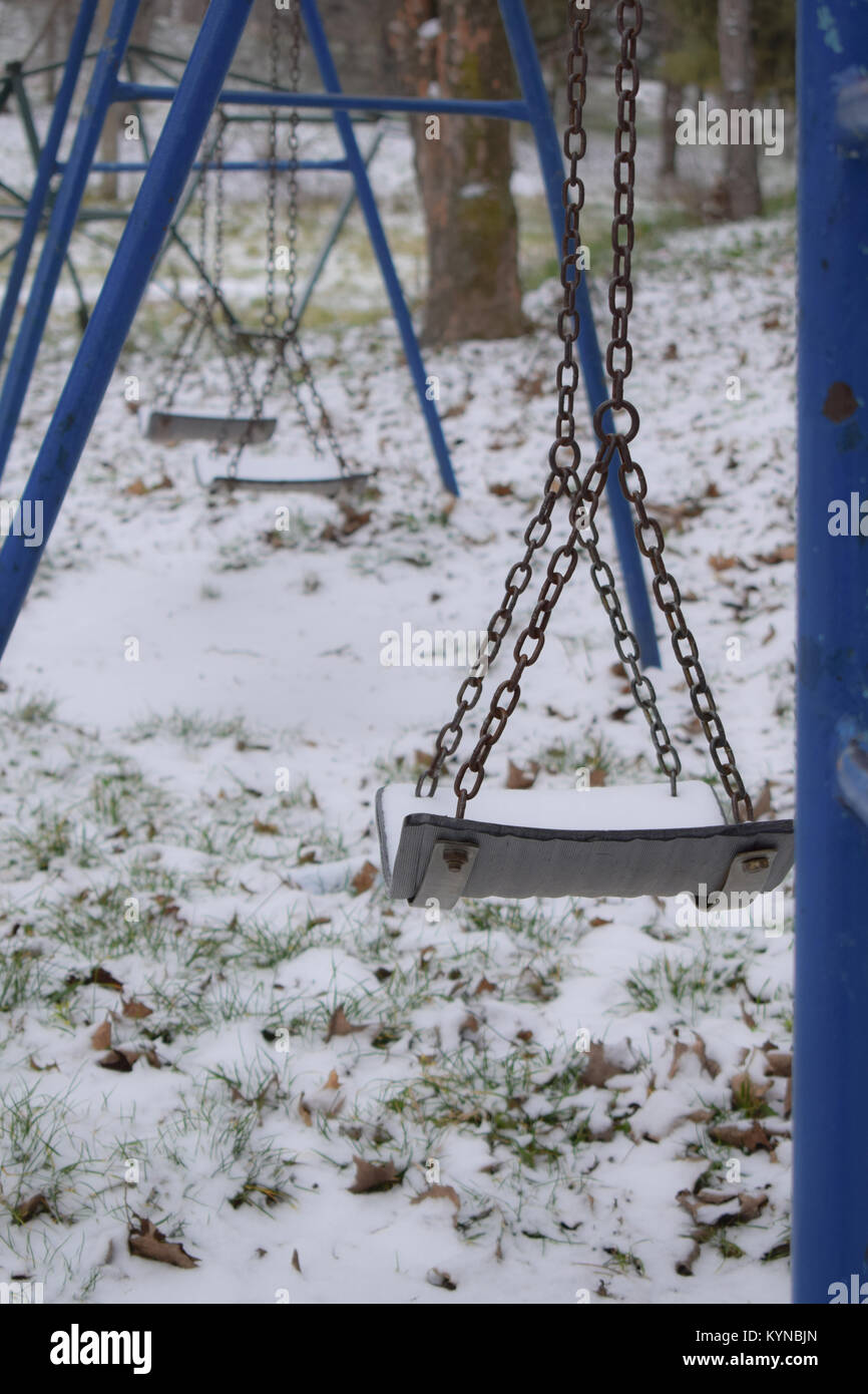 Lonely blue balançoires dans le parc de jeux sur la neige, hiver Banque D'Images