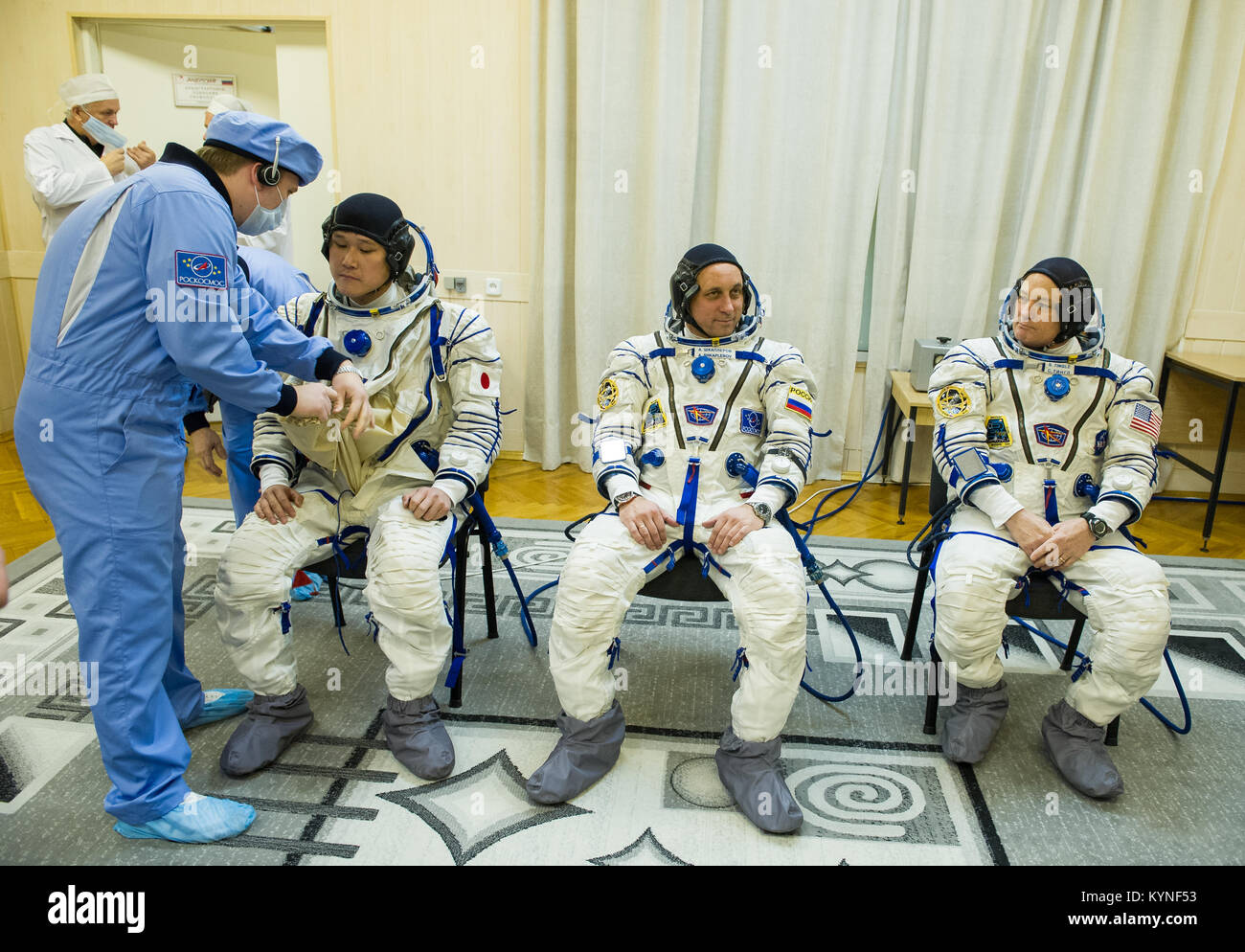 L'ingénieur de vol de l'expédition 54 Norishige Kanai de l'Agence japonaise d'exploration aérospatiale (JAXA), à gauche, est aidé dans son costume Sokol russe comme lui et ses collègues incinère, commandant de Soyouz Anton Shkaplerov de Roscosmos, centre, et l'ingénieur de vol de la NASA Scott Tingle, droite, se préparer pour leur lancement Soyouz à la Station spatiale internationale Dimanche, Décembre 17, 2017 à Baïkonour, au Kazakhstan. Lancement de la fusée Soyouz enverra Tingle, Kanai, Shkaplerov et sur une mission de cinq mois à bord de la Station spatiale internationale. Crédit photo : NASA/GCTC/Andrey Shelepin) Banque D'Images