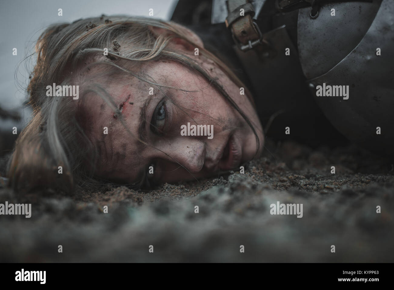 Fille avec des blessures sur son visage dans l'image de Jeanne d'Arc se trouve dans la boue en armure. Libre. Banque D'Images