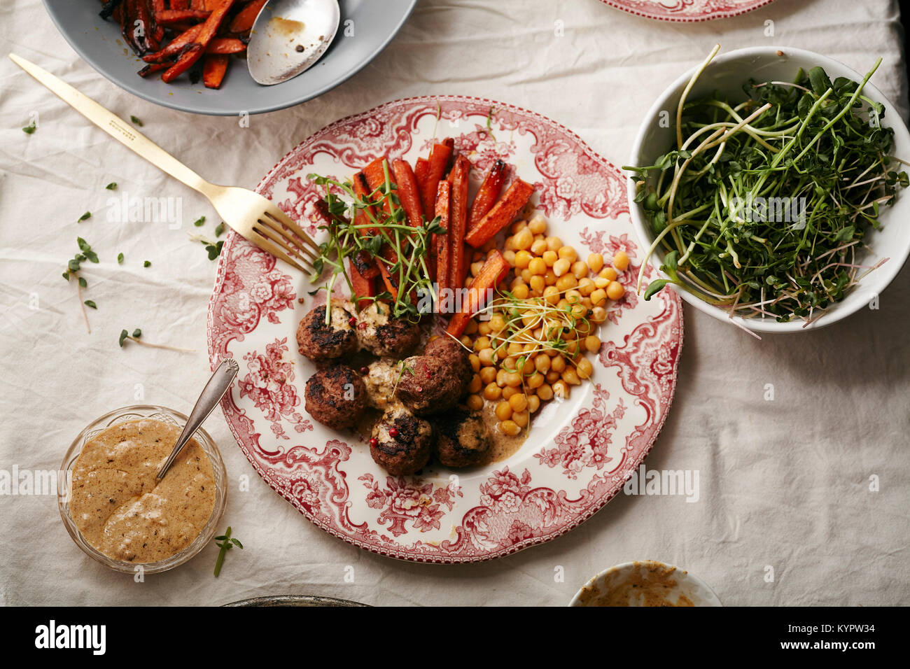 Swedish meatballs garni de sauce béchamel et micro-verts avec les pois chiches et les carottes caramélisées servi sur plaque porcelaine vintage sur l'onglet linge Banque D'Images