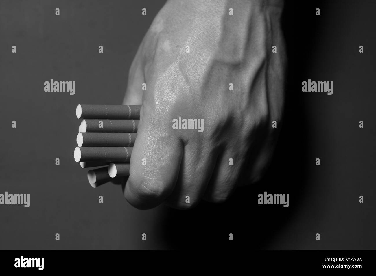 La dépendance au tabac. La cigarette sur l'homme de main sur fond noir. Banque D'Images