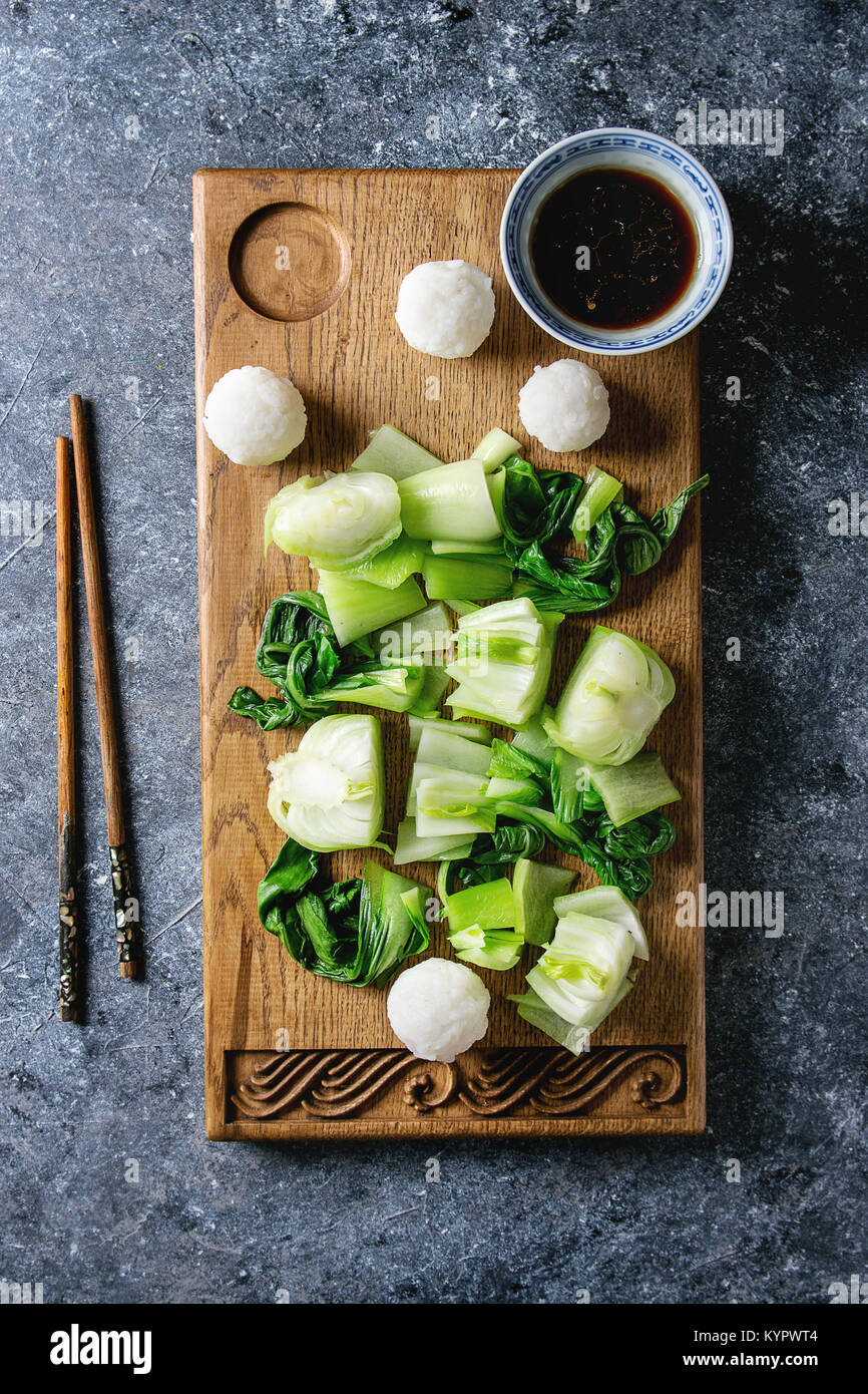 Sauté de bok choy ou chou chinois avec de la sauce soja et de boules de riz servi sur planche à découper en bois décoratif avec des baguettes sur la texture gris backg Banque D'Images