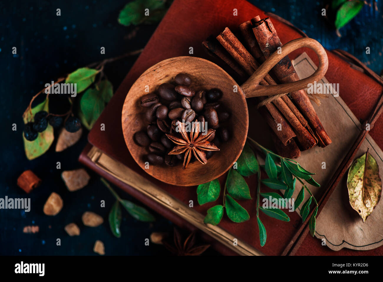 Bol en bois avec les grains de café sur un fond sombre avec des étoiles d'anis, la cannelle, le sucre brun et les feuilles. Vintage still life with barista ustensiles. Brewi Banque D'Images