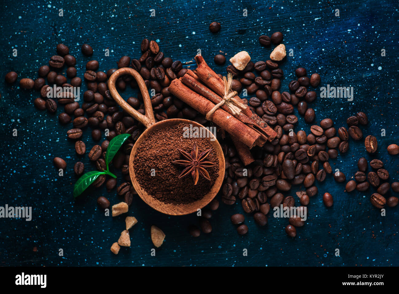 Cuillère en bois avec du café moulu, l'anis étoile, la cannelle, le sucre brun et les feuilles sur un fond foncé Vintage still life with barista ustensiles. Brewing Banque D'Images