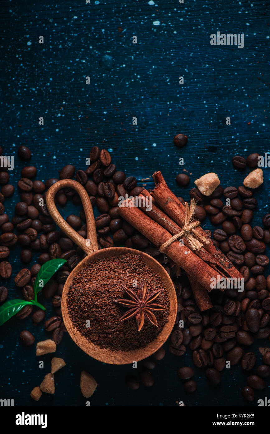 Cuillère en bois avec du café moulu, l'anis étoile, la cannelle, le sucre brun et les feuilles sur un fond foncé Vintage still life with barista ustensiles. Brewing Banque D'Images