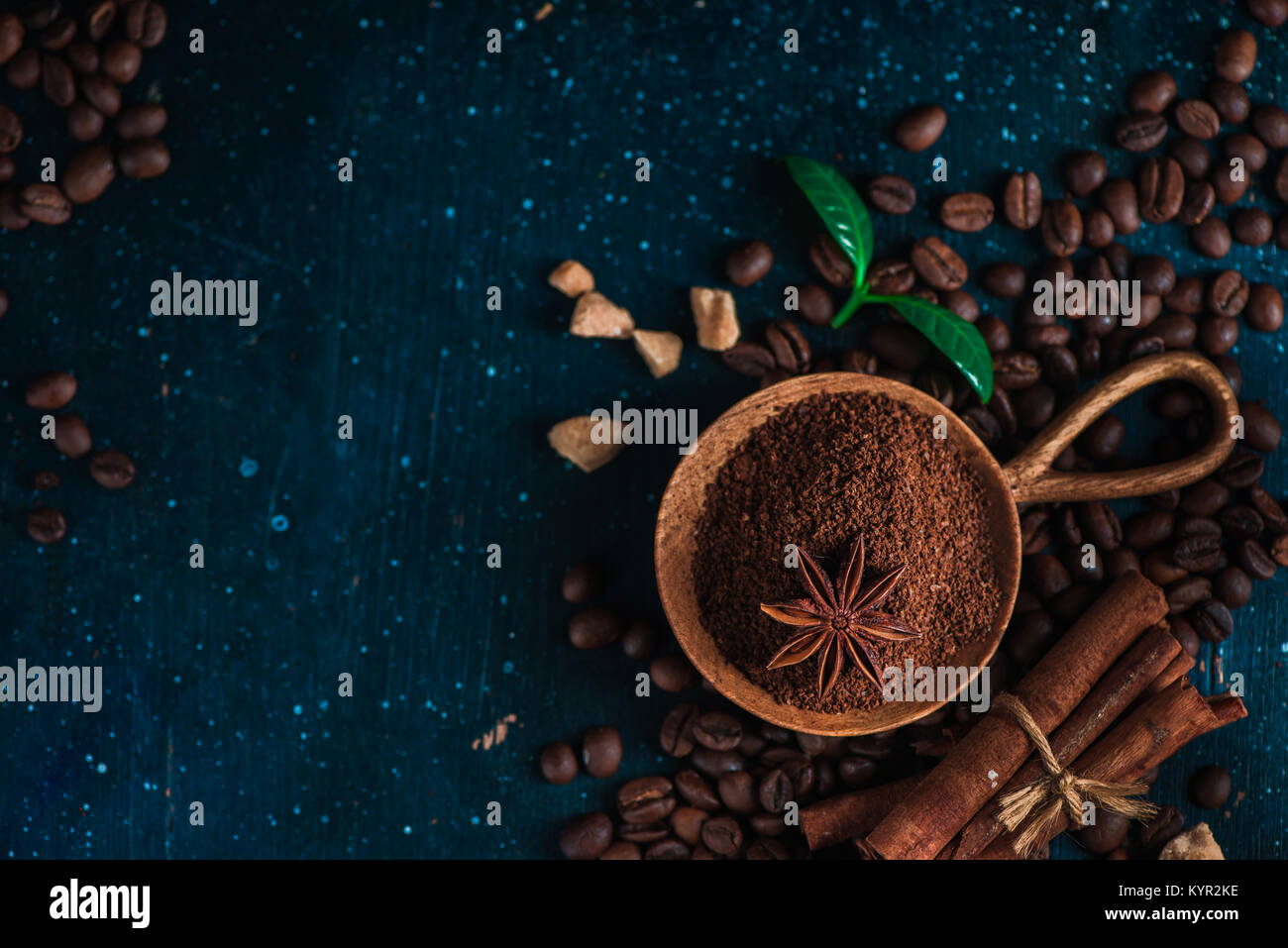 Café dans un bol en bois avec de l'anis étoile, la cannelle, le sucre brun et les feuilles sur un fond sombre. Vintage still life with barista ustensiles. Brew Banque D'Images