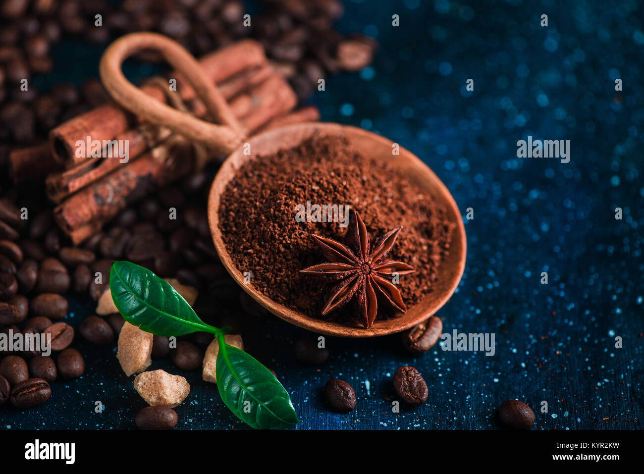 Café dans un bol en bois avec de l'anis étoile, la cannelle, le sucre brun et les feuilles sur un fond sombre. Vintage still life with barista ustensiles. Brew Banque D'Images