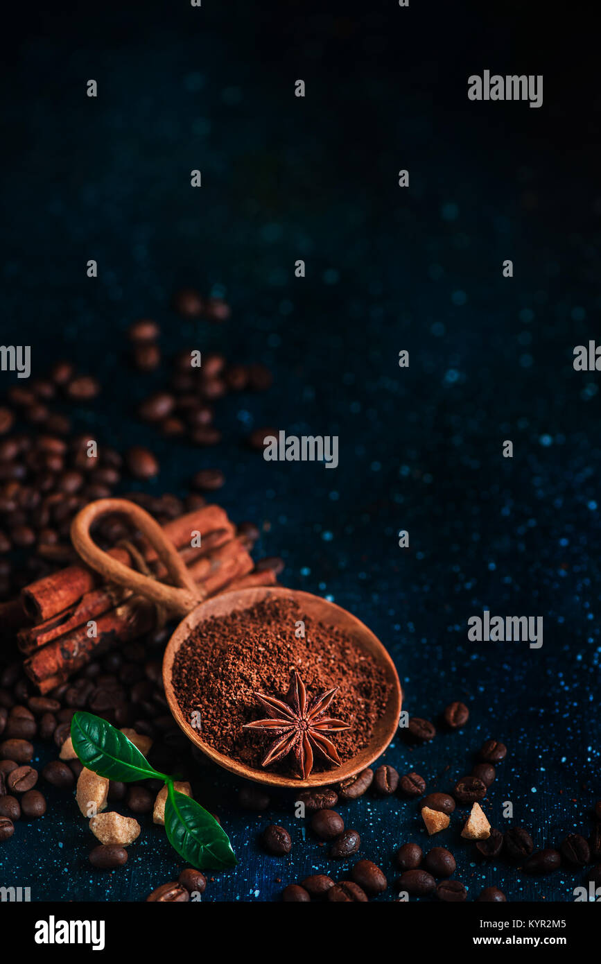 Cuillère en bois avec du café moulu, l'anis étoile, la cannelle, le sucre brun et les feuilles sur un fond foncé Vintage still life with barista ustensiles. Brewing Banque D'Images