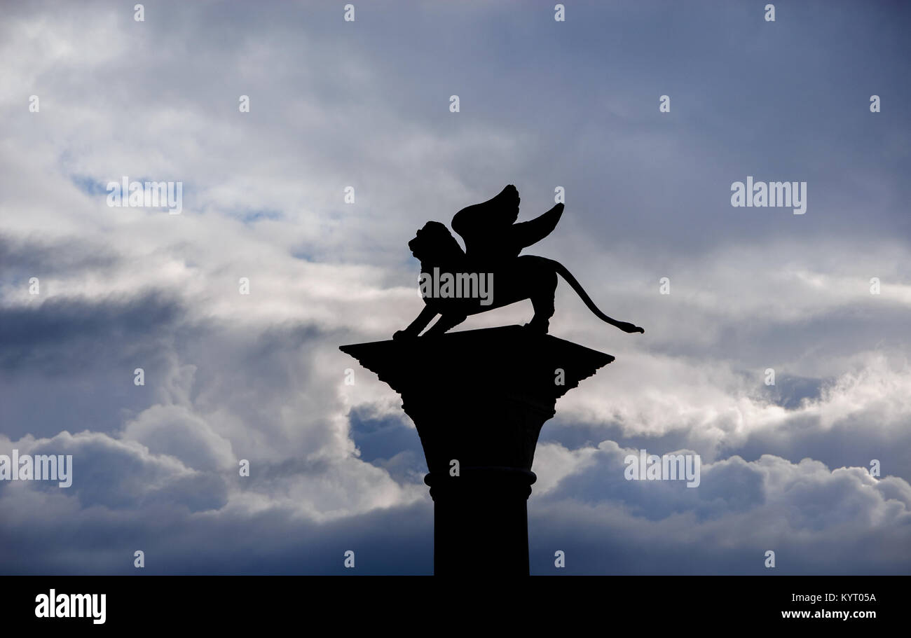 Lion ailé de Saint Marc vieille statue silhouette parmi les nuages Banque D'Images