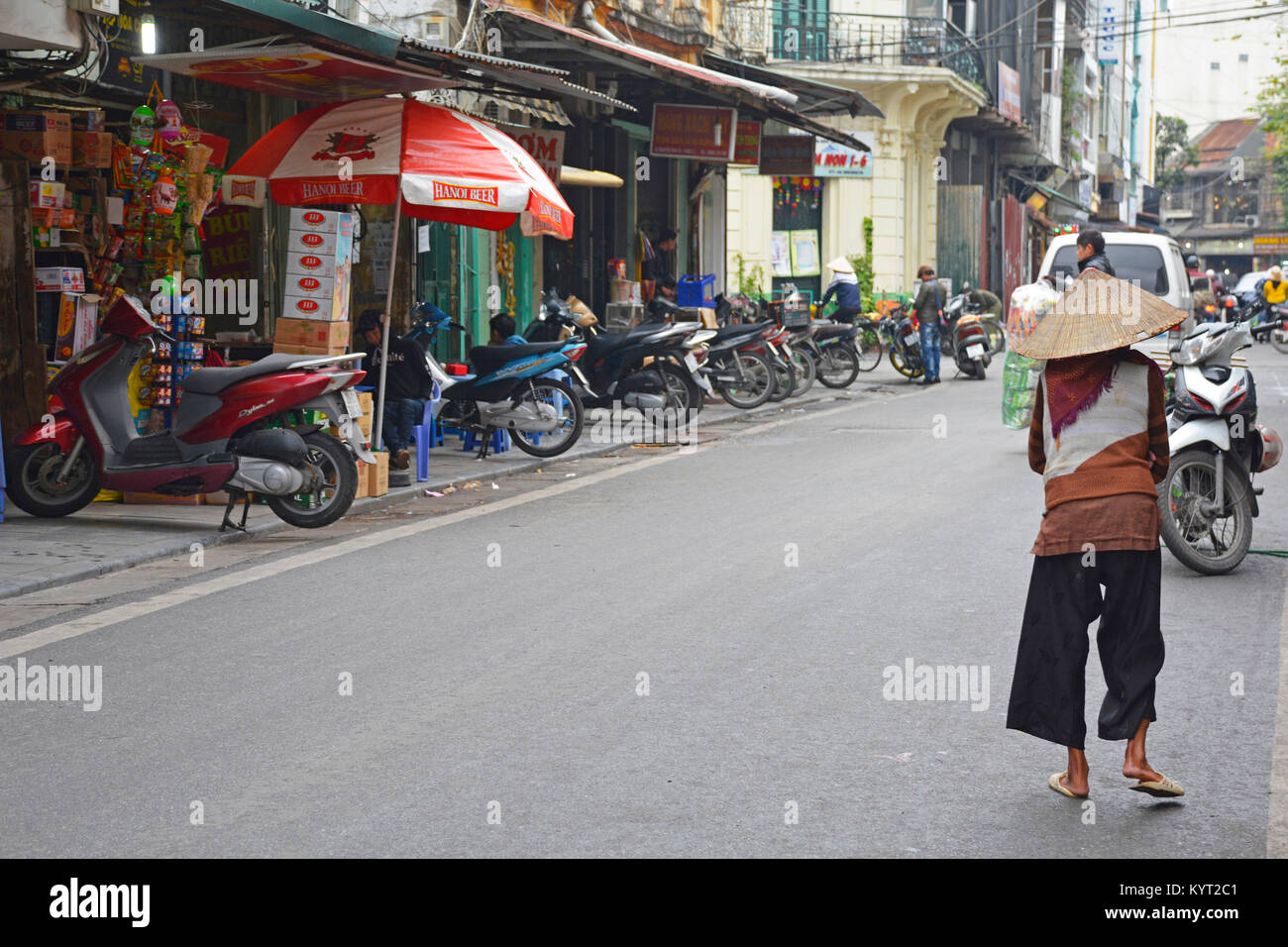 Hanoi, Vietnam - 14 décembre 2017. Une femme âgées en vêtements traditionnels et hat marche dans une rue dans le vieux quartier historique de Hanoi Banque D'Images