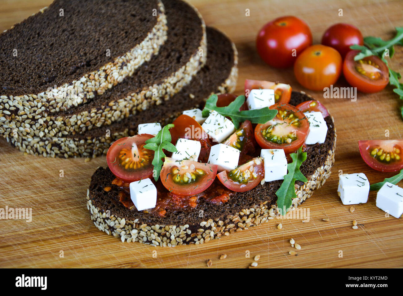 Sandwich juteux avec tomates, fromage et herbes sur fond noir avec des céréales pain Banque D'Images