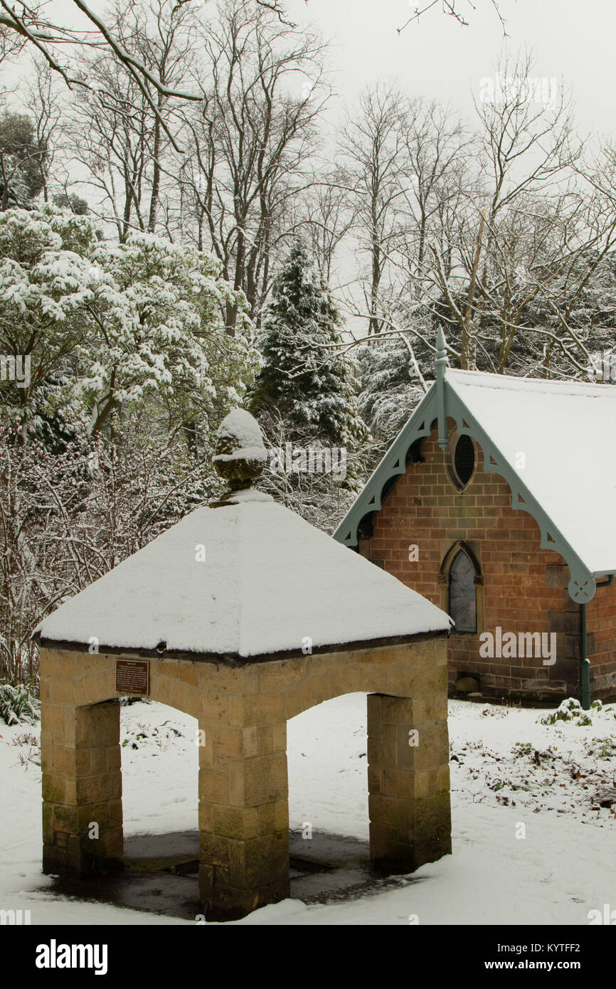 Une source minérale couvertes de neige avec l'ancienne salle des pompes et de magnésie dans l'arrière-plan Valley Gardens, Harrogate, North Yorkshire, Angleterre, Royaume-Uni. Banque D'Images